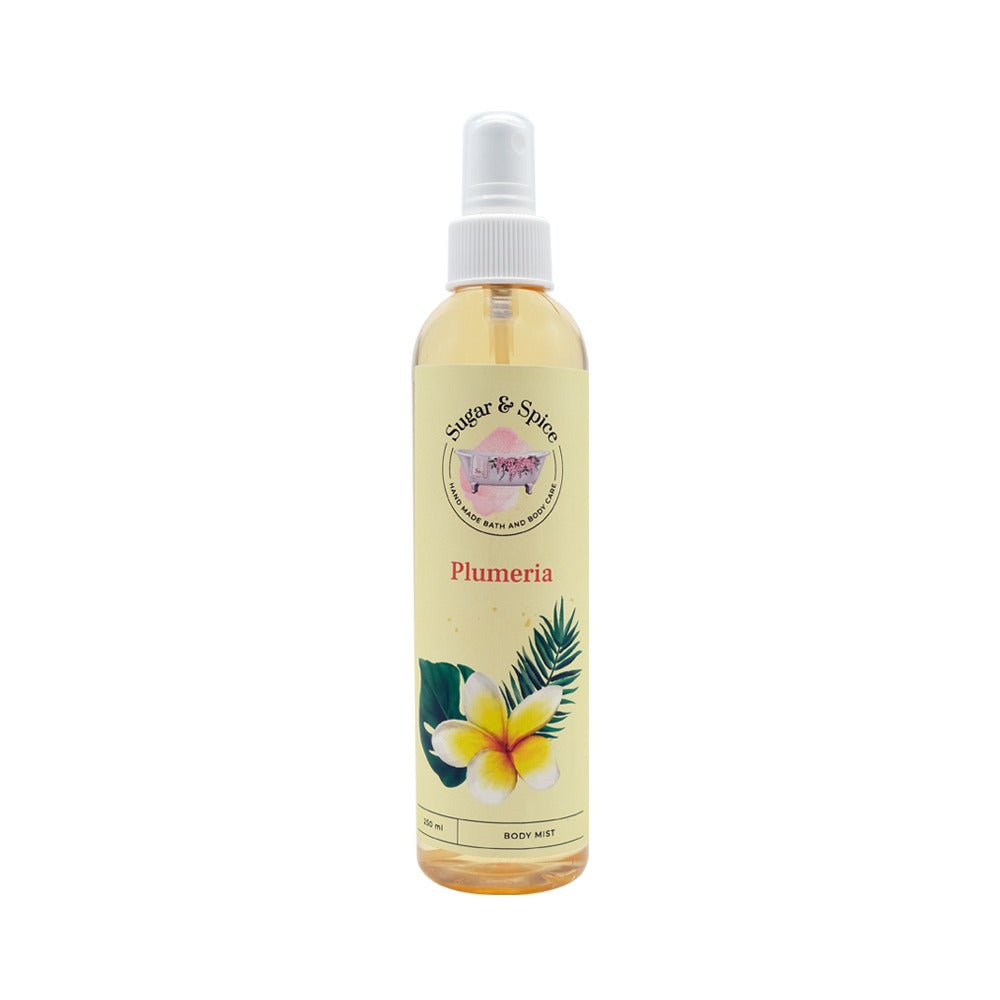 A bottle of Plumeria Body Mist with a white spray nozzle. The label features the name 'Plumeria' and an illustration of a plumeria flower with green leaves.