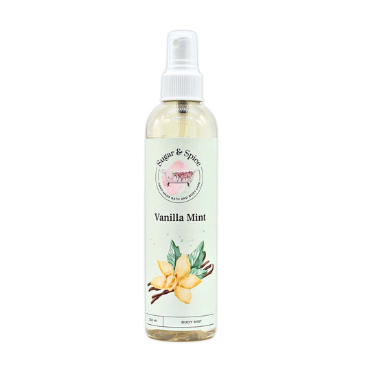 A bottle of Vanilla Mint Body Mist with a white spray nozzle. The label shows the name 'Vanilla Mint' and an illustration of a vanilla flower.